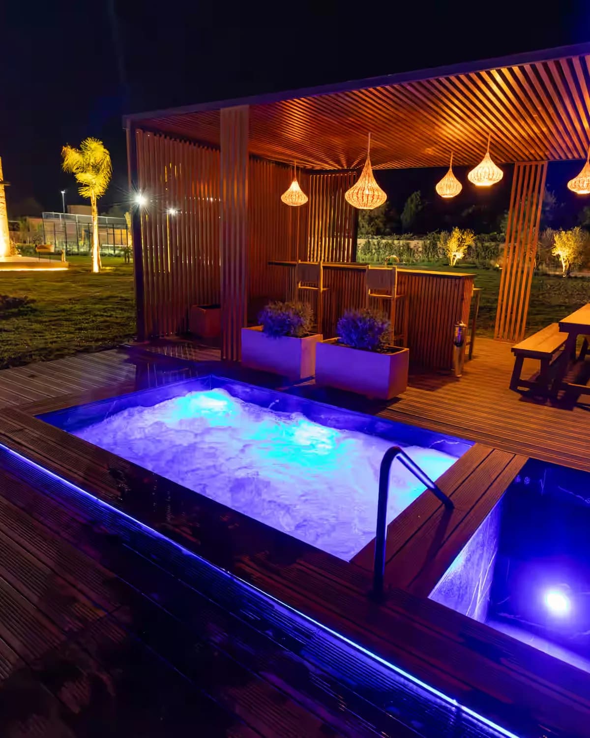 De verwarmde jacuzzi en het koudwaterbad op het houten terras, bij avond verlicht